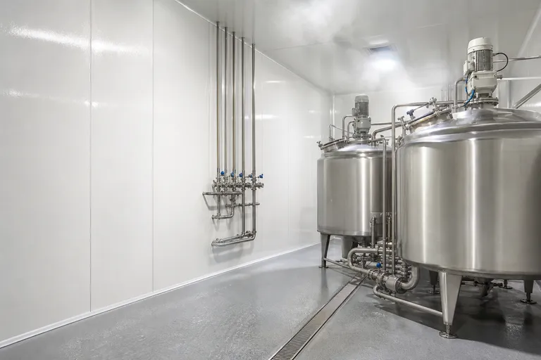 Stainless steel processing tanks in a dairy processing room with FRP gelcoat wall panels